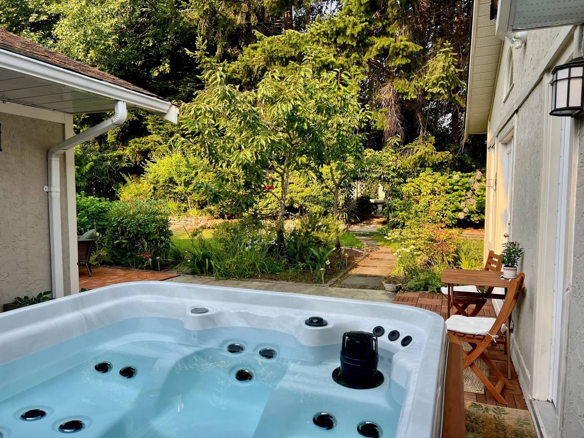 Private hot tub overlooking a lush garden with mature evergreen trees