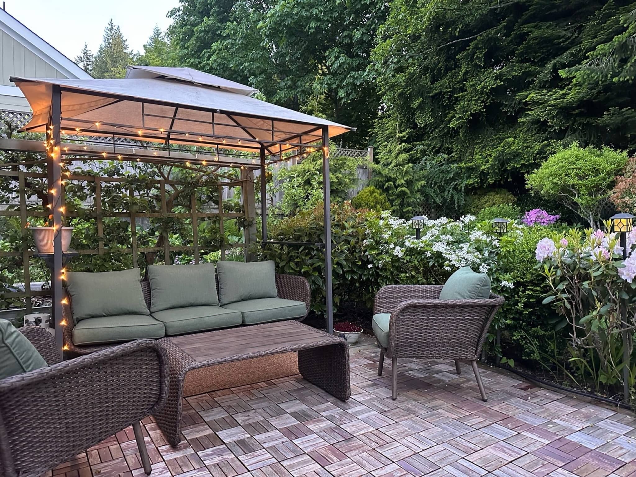 Private backyard patio with wicker furniture and green cushions