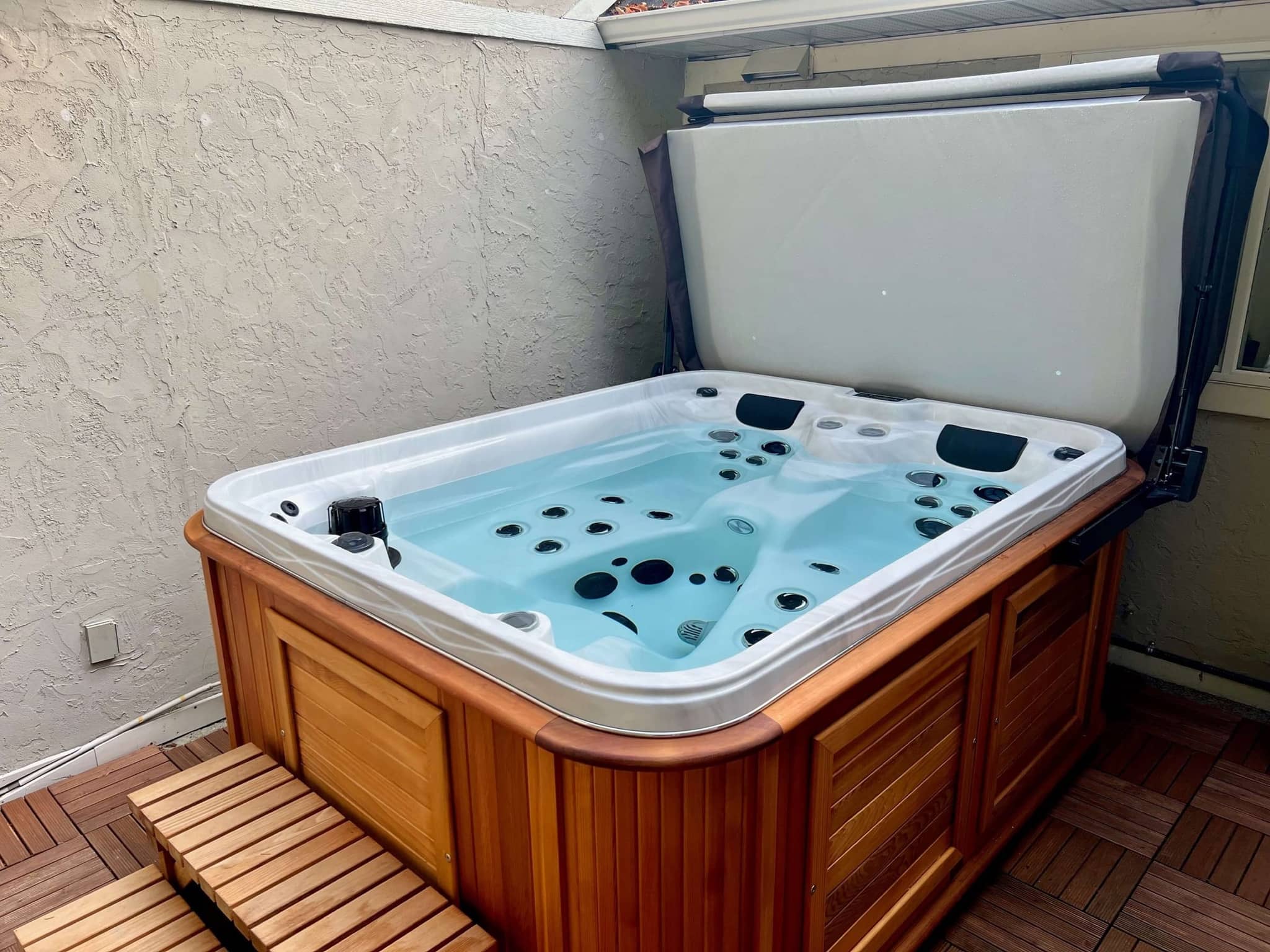 Salt-water Arctic Spa hot tub with wooden surround and partly open cover