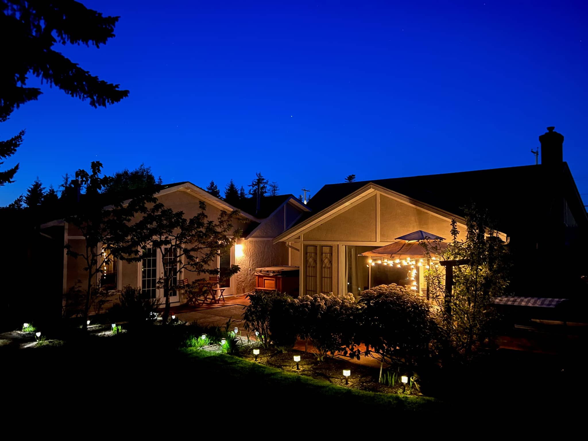Five Gables suite at blue hour, with warm windows, string lights and garden path lights