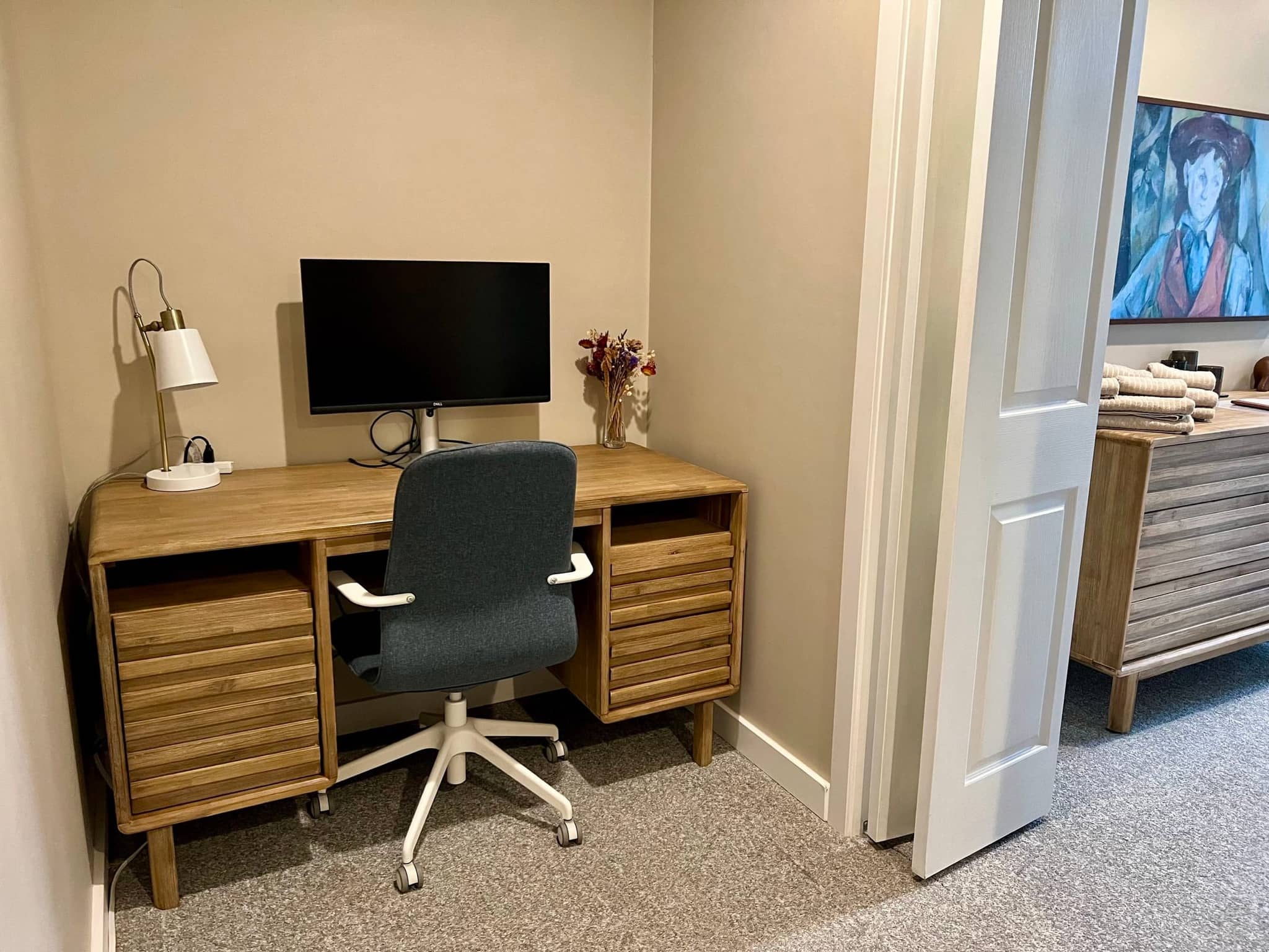 Dedicated workspace with wooden desk, 27-inch monitor and desk lamp